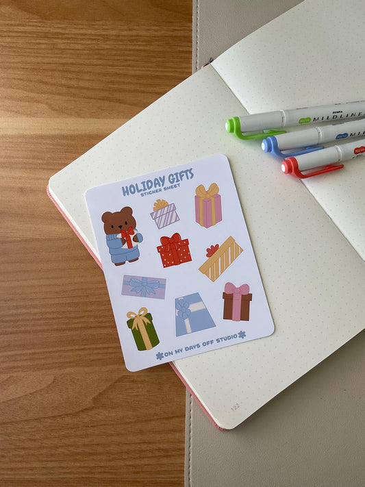 Holiday gifts sticker sheet front, featuring 1 illustration of a cute bear wearing winter sweater holding a present. Also, it includes 8 colorful gifts or present boxes. 