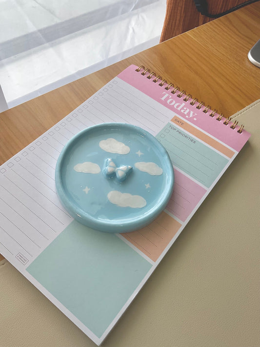 Dreamy handmade clay jewelry dish with clouds painted on and a 3D butterfly in the center. 