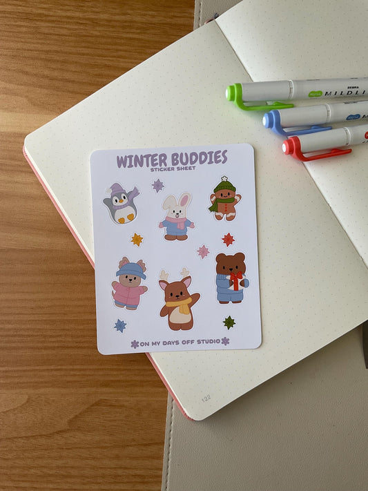 winter buddies sticker sheet front, featuring 6 illustrations of cute animals wearing winter clothes and accessories. This includes a penguin, bunny, gingerbread man, bear, deer and dog. Also, it includes 6 colorful stars. 