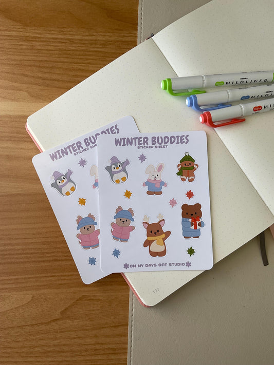 winter buddies sticker sheet front, featuring 6 illustrations of cute animals wearing winter clothes and accessories. This includes a penguin, bunny, gingerbread man, bear, deer and dog. Also, it includes 6 colorful stars. 